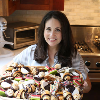 Shannon Sarna smiling in front of a large selection of deserts